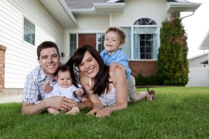 family on grass in front of house.