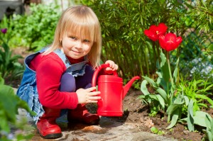 Little girl posing with  red watering can