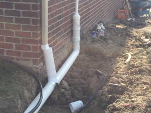 Residential Drainage System Creation on the side of a brick house.