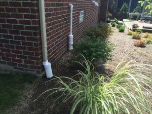 French drains installed on the side of a brick building.