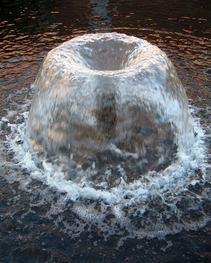 A water fountain creating ripples in the pond.