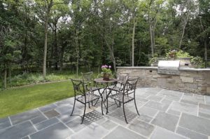 Beautiful paver patio with table and chairs and a built in grill.