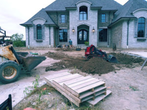 in progress of paver driveway photos. piles of dirt and machinery are seen.