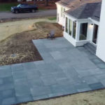after photos of a grey stone patio connected to a white house