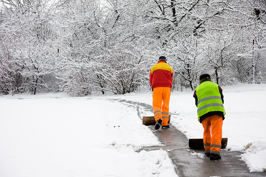 Workers removing first snow from pavement in nice neighborhood.