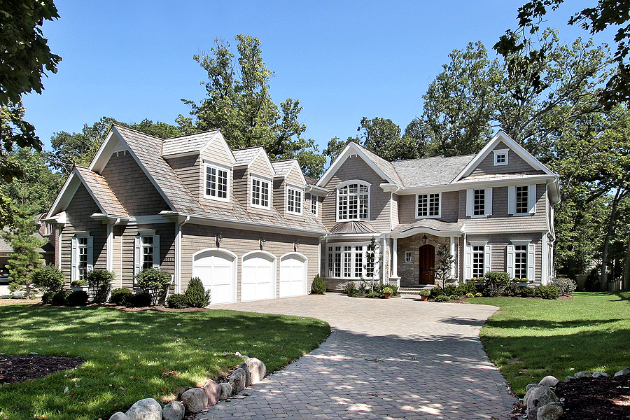 Luxury new home with lush green lawn and professional landscaping around the front of the house.