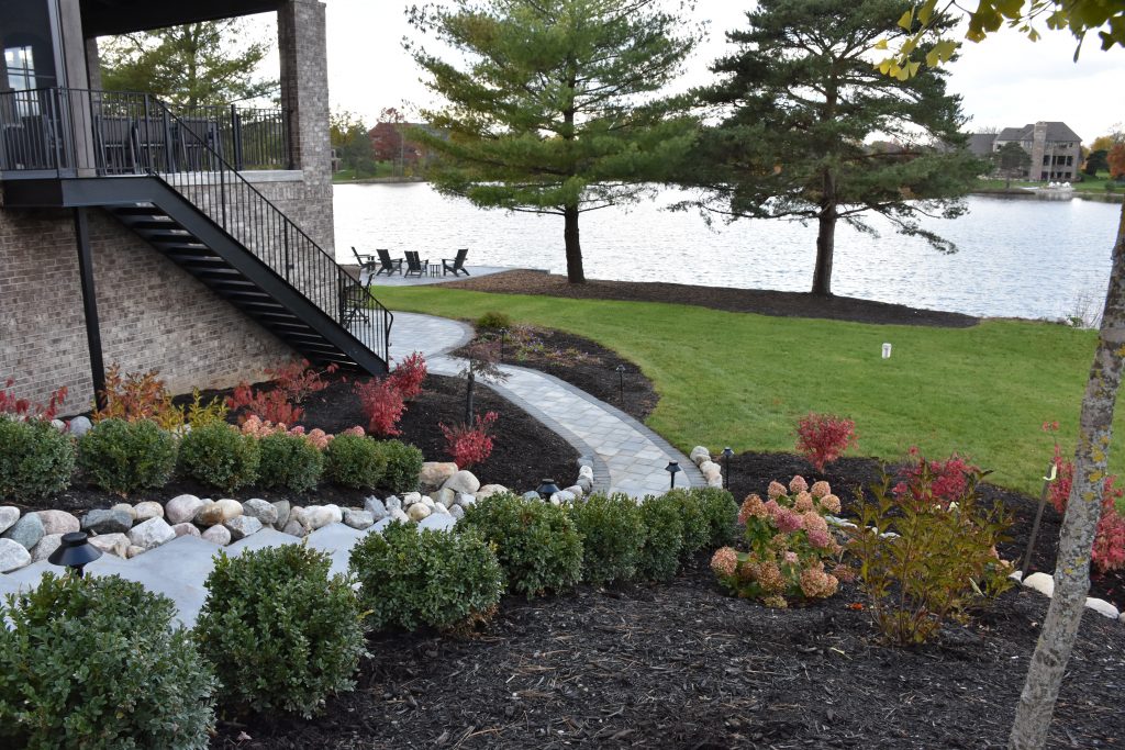 brick pathway leading down to a patio with a lake view