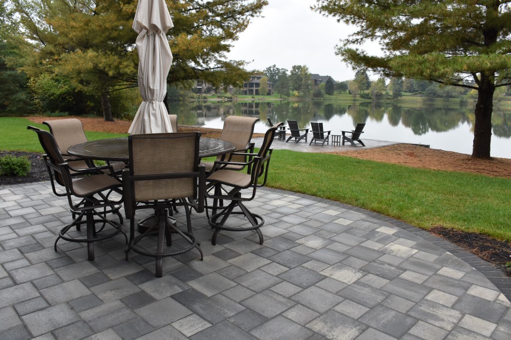 Beautiful paver patio with a patio table set on top overlooking a lake