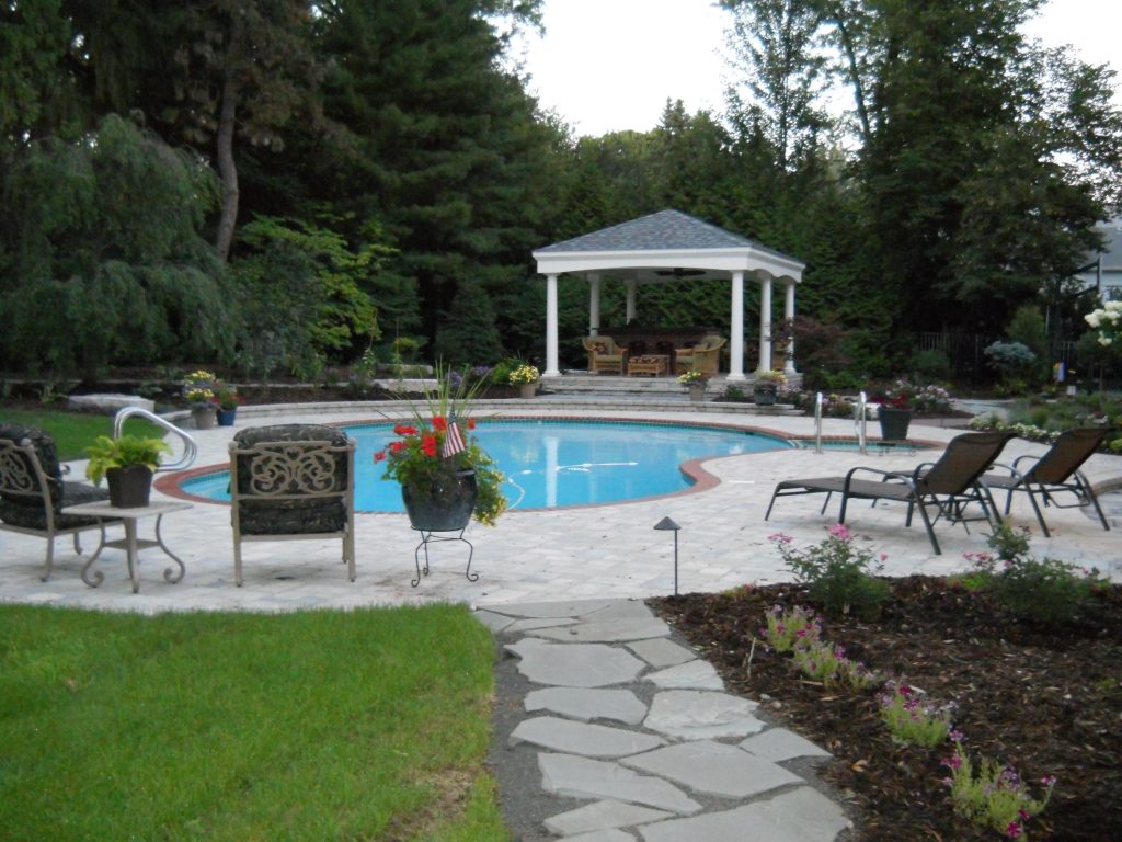 Paved patio surrounds a beautiful pool area with a gazebo in Ann Arbor