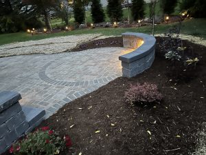 circular paver patio with landscape lighting on retaining wall